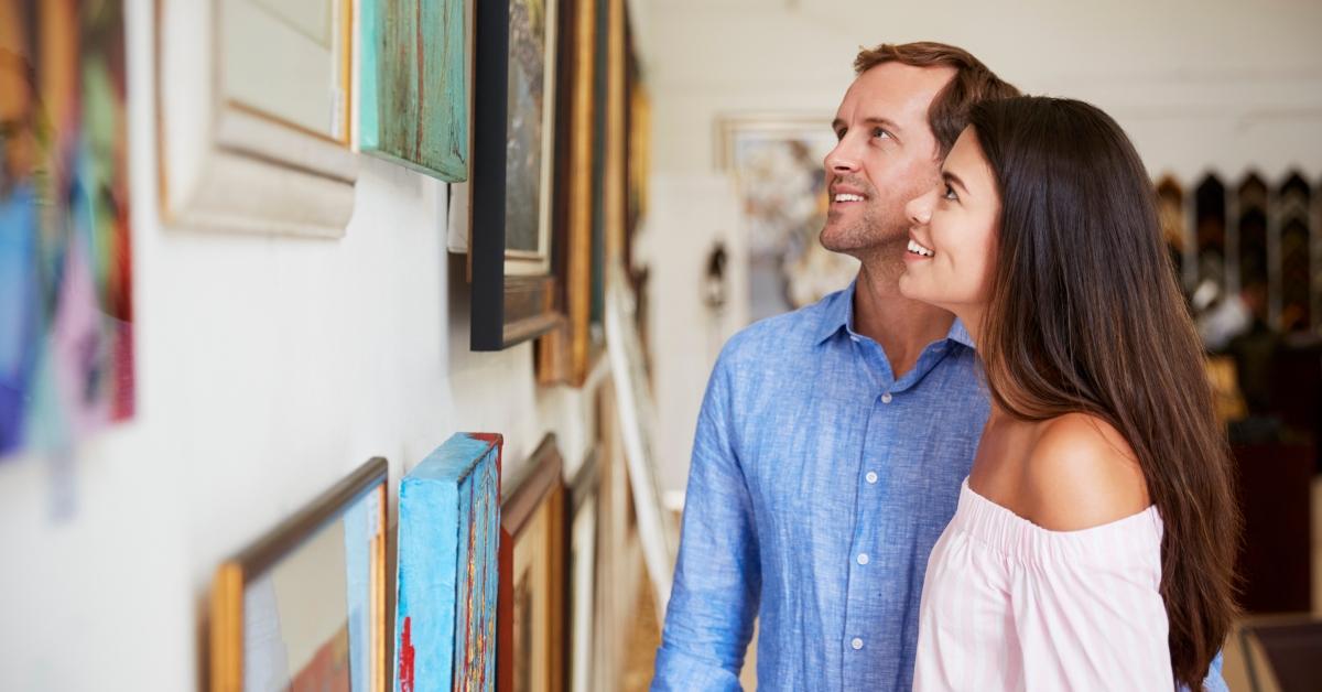 couple looking at paintings in art gallery together