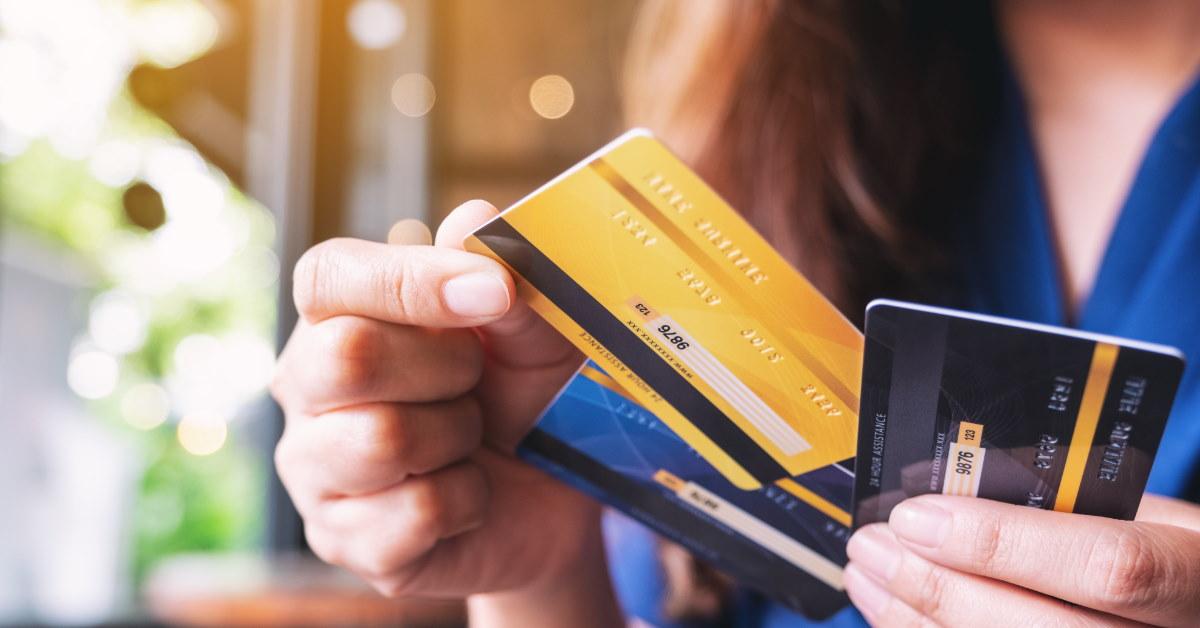 woman holding three different cards in hand choosing one to make payments