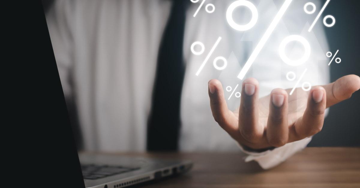 man holding 3d percentages in hand while using laptop 