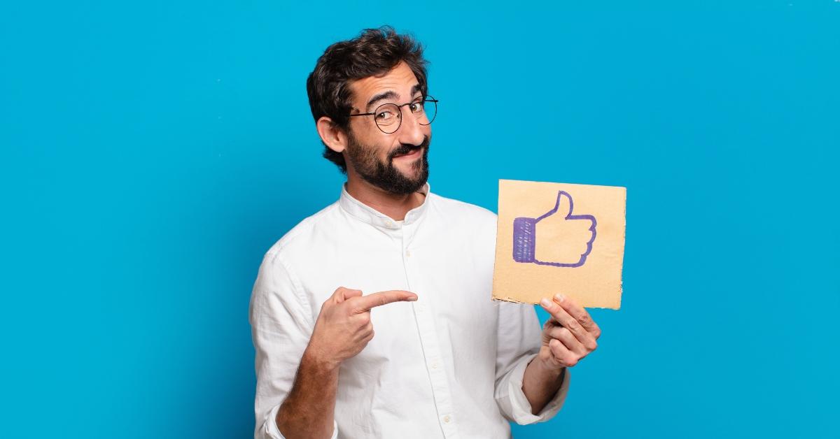 young bearded man holding a social media like banner