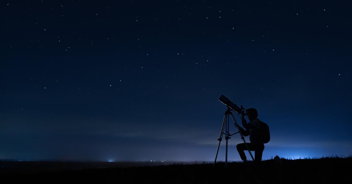 woman looks through a telescope at the starry sky