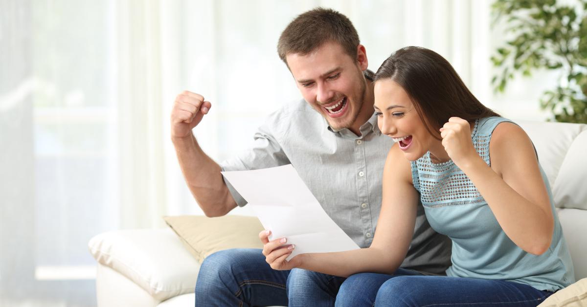 excited couple reading a letter at home