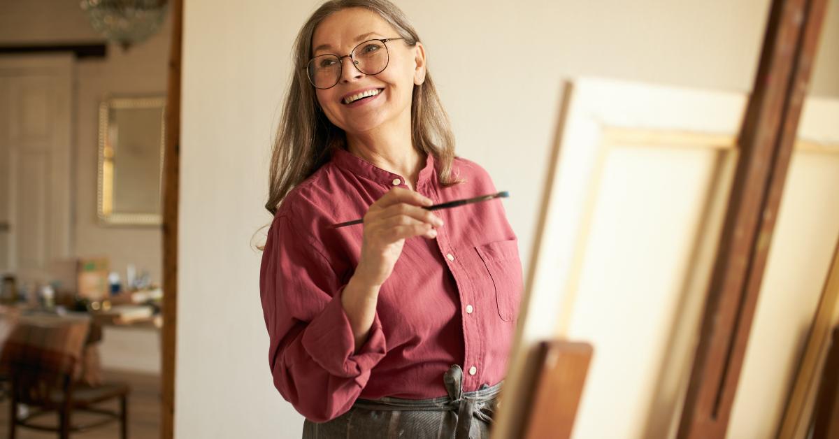 female pensioner in apron and eyeglasses painting