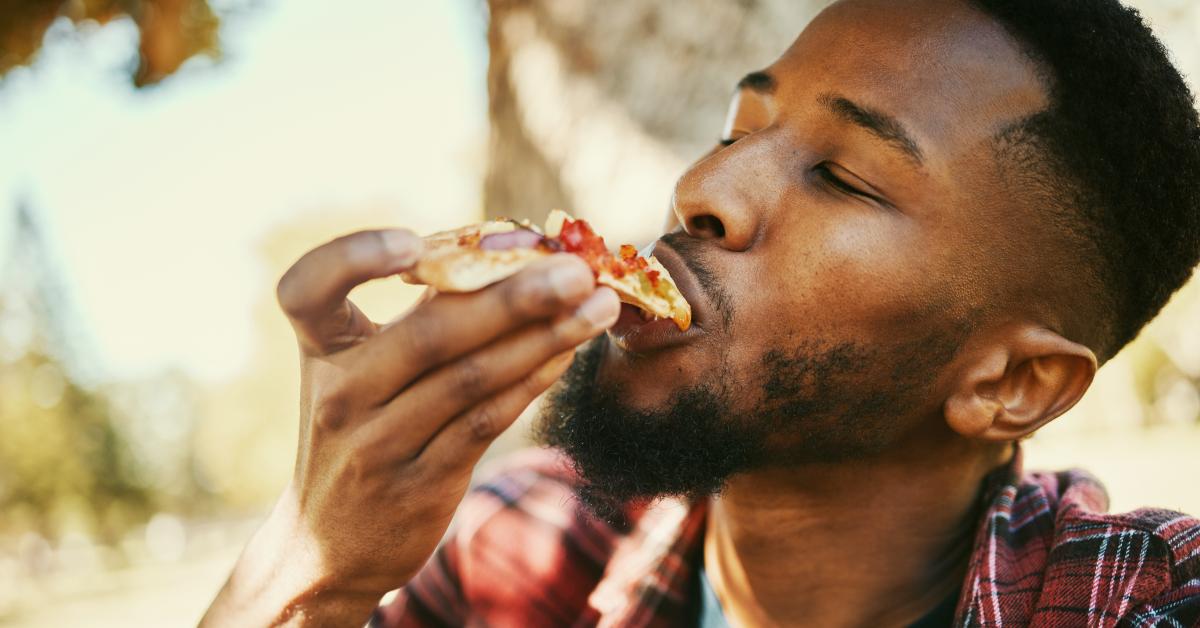 black man eating pizza