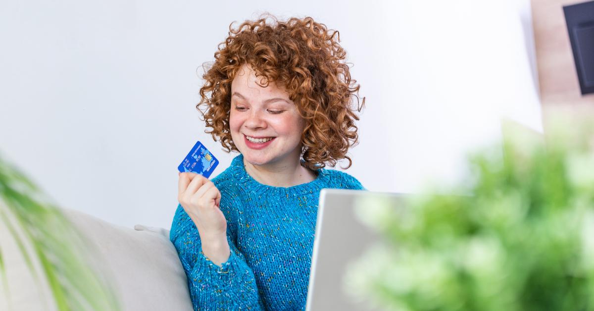 young woman holding credit card and using laptop computer