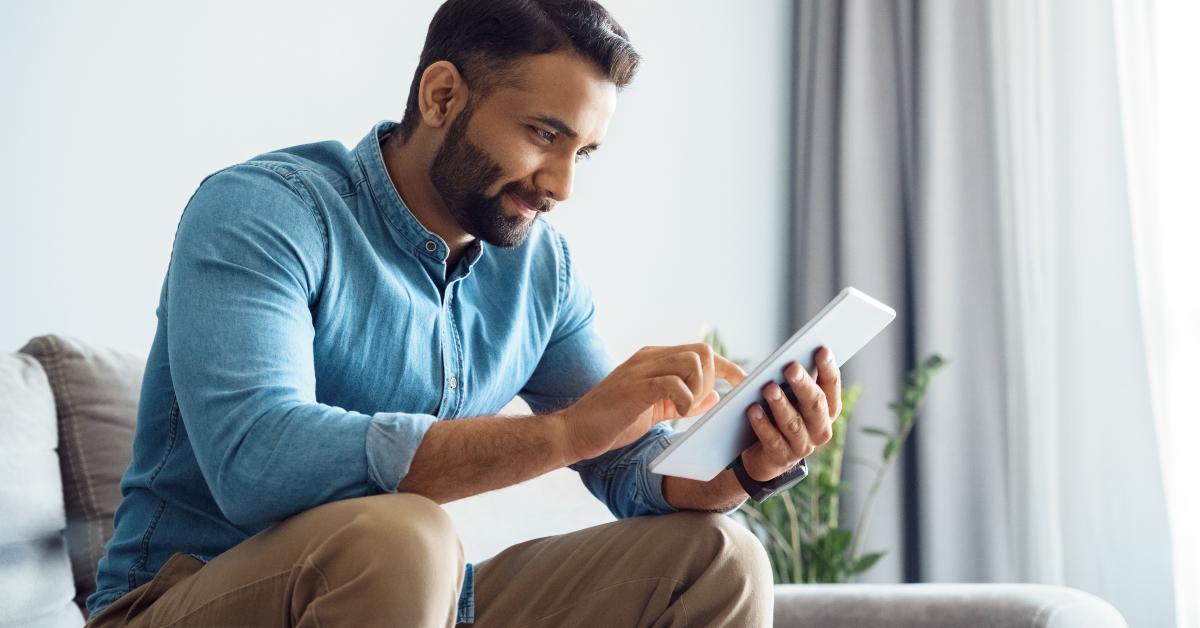 man using tablet relaxing on couch sofa