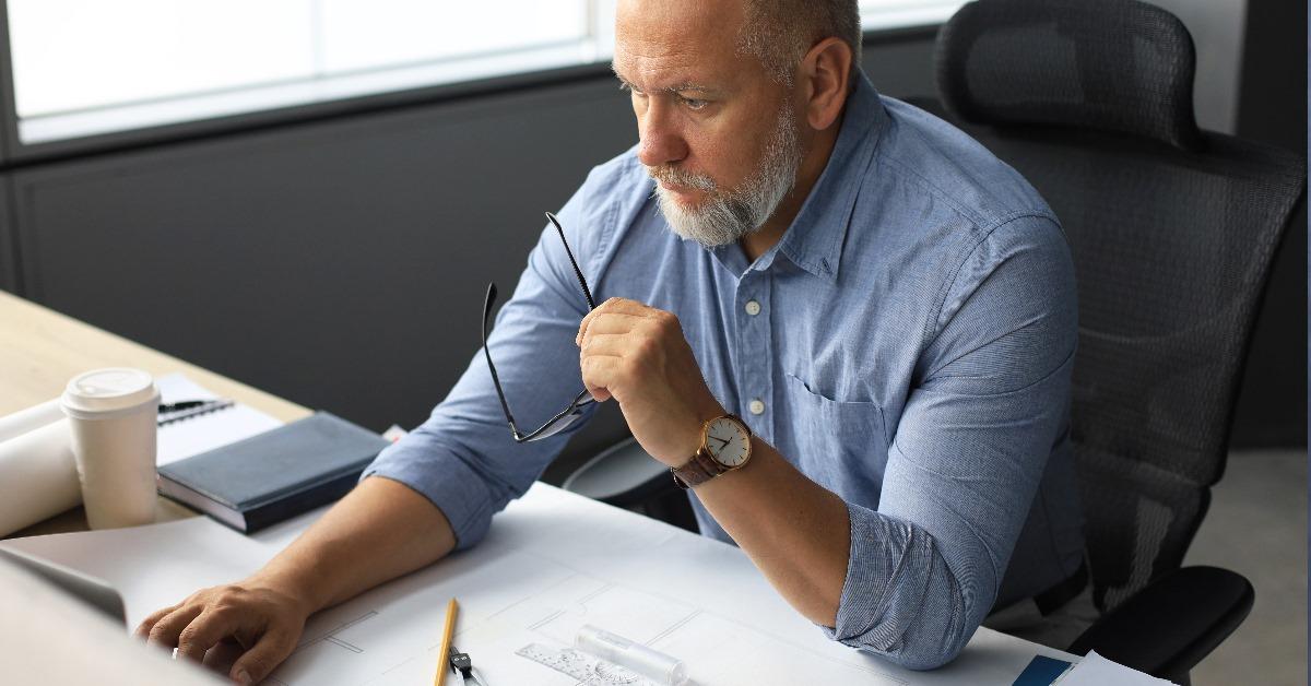 senior businessman sitting on desk with bunch of papers at office