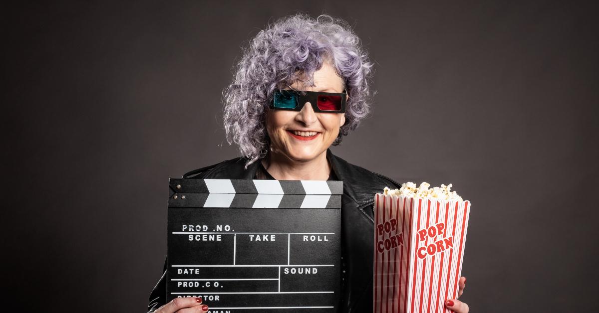 older woman holding popcorn and movie clapper
