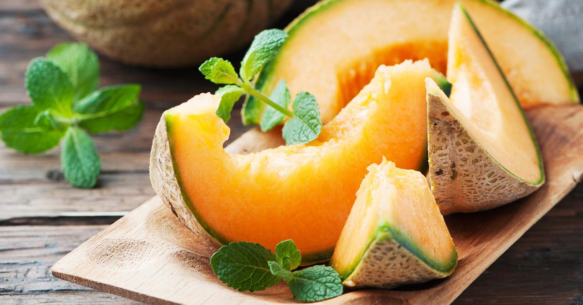sweet orange melon garnished with mint leaves in wooden tray