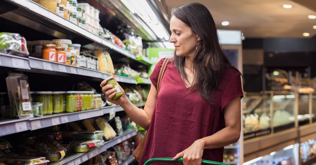 woman checking bottle of green sauce in supermarket.