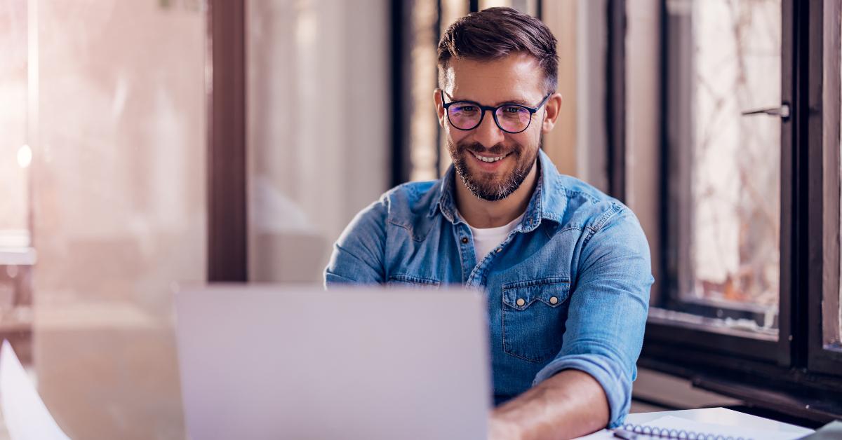 smiling businessman sitting in office and working on laptop