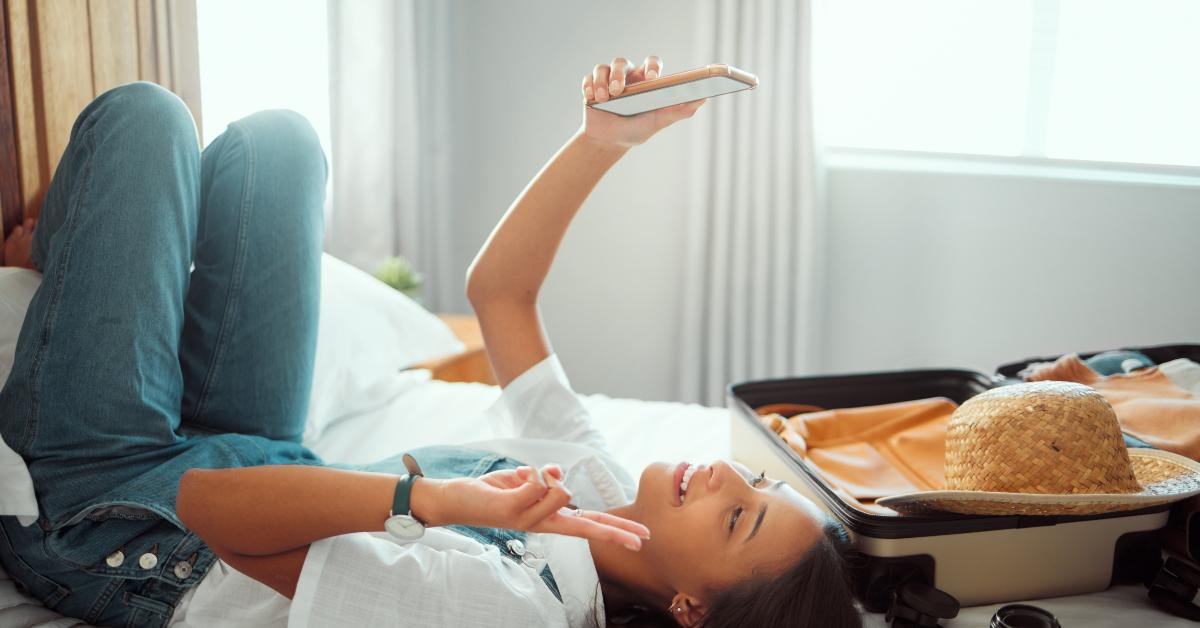 girl taking selfie on a bed for social media with luggage