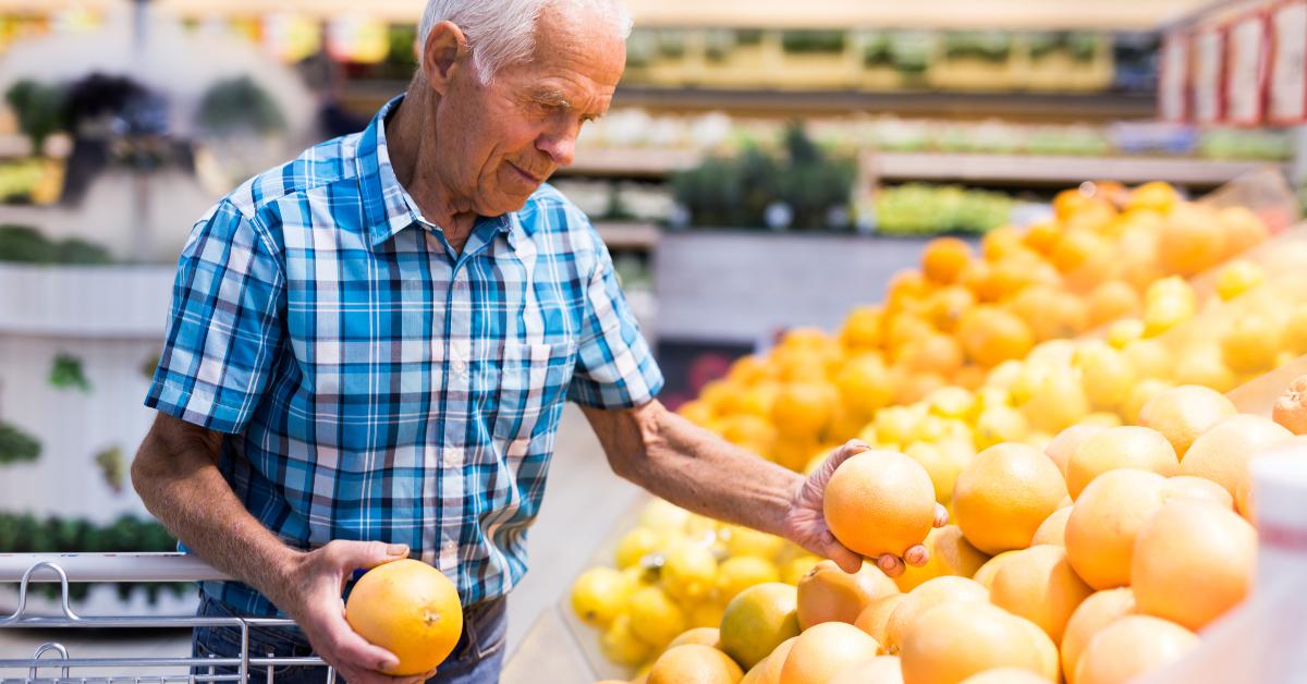 elderly retired man buying oranges in the grocery