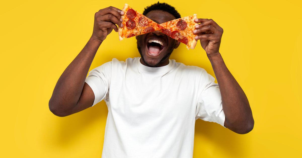 Man in white t-shirt holds pizza