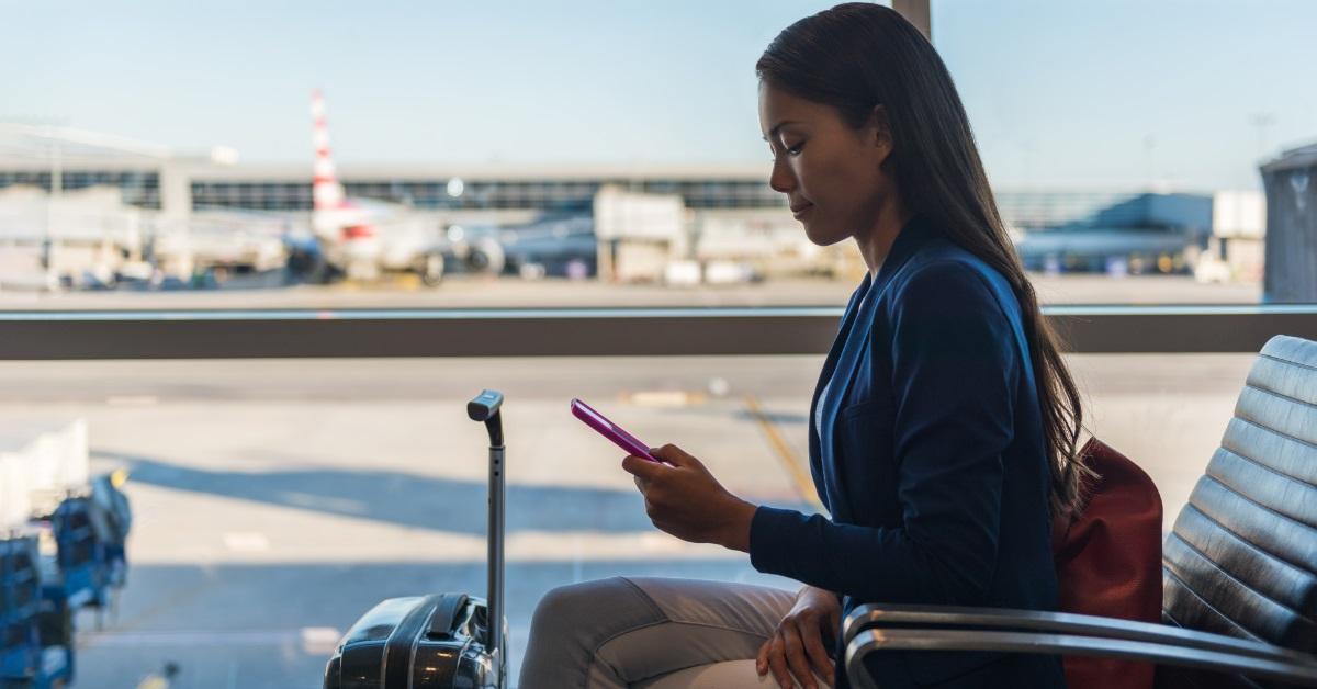 woman waiting at airport using smartphone