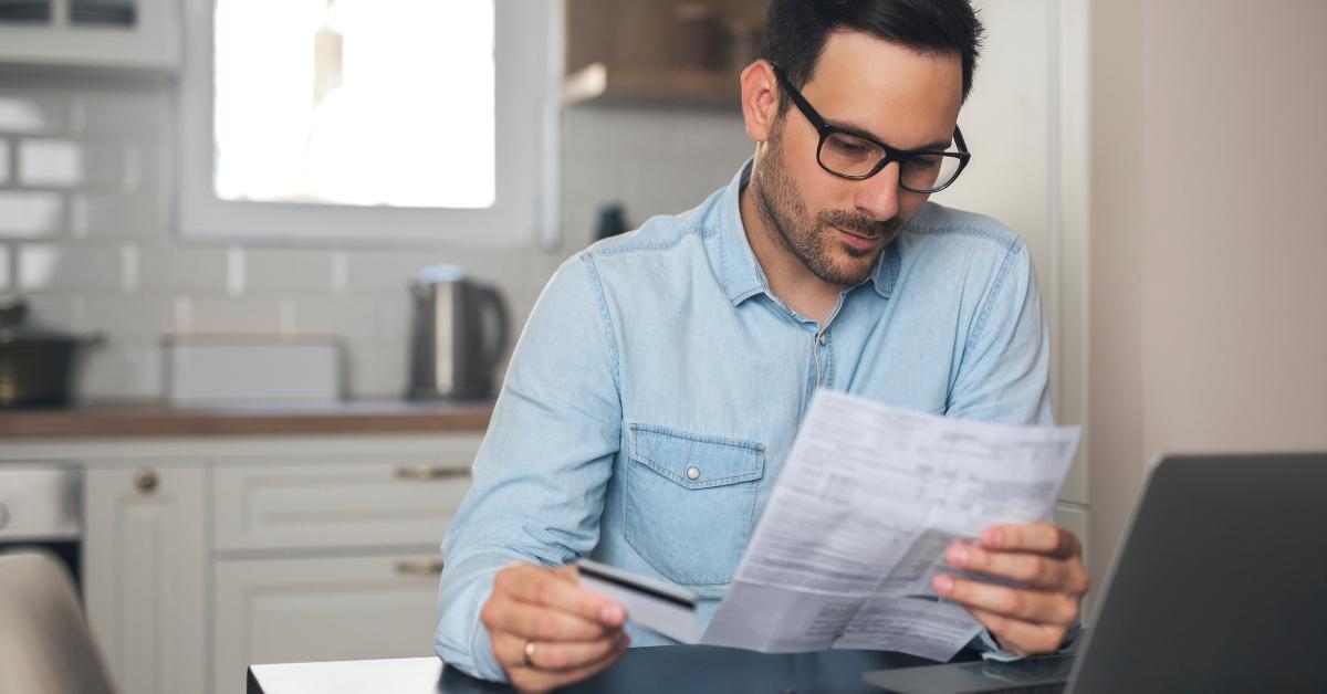 man holding credit card and paper