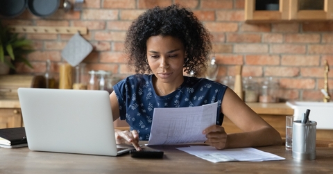 Woman looking at paperwork and using calculator