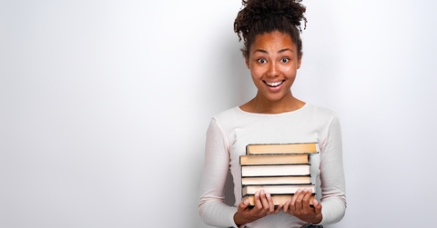 Young African American woman holding a stack of books 