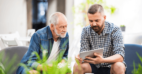 Father and son talking and looking at tablet