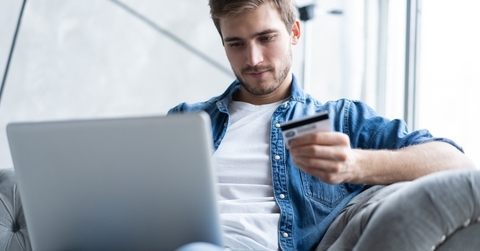 Man holding credit card and looking at laptop