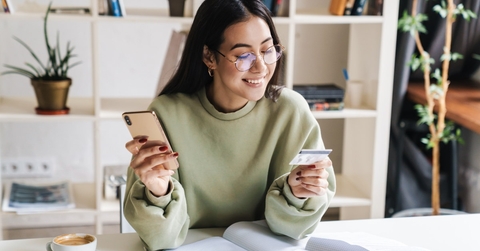 happy woman holding card and smartphone in hands