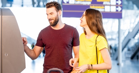 Couple withdrawing money from an ATM at an airport