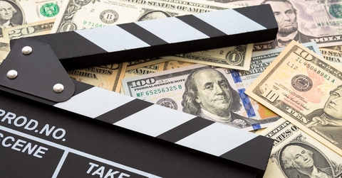 A movie clapboard on top of a pile of cash.