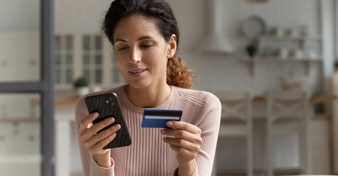 Smiling woman looking at phone and holding credit card