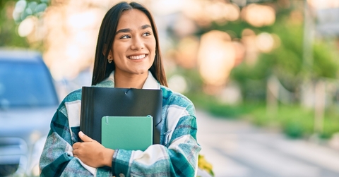 Smiling college student holding notebooks