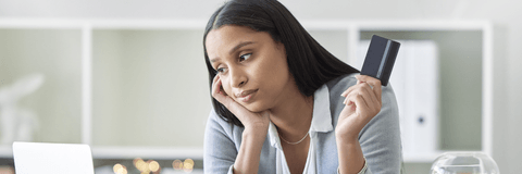 Woman holding a credit card looking stressed