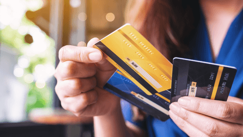 A woman holds three credit cards in her hands. 
