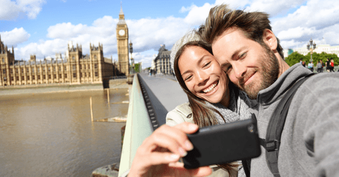 A woman and man smile together on a bridge while taking a picture.