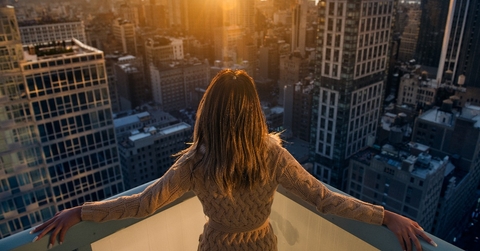 Rich woman enjoying the sunset standing on the balcony of a luxury apartments in New York City