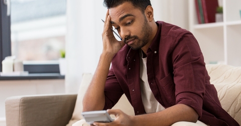 confused man with calculator at home