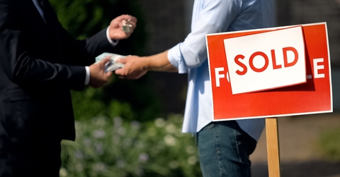 People shaking hands by 'sold' house sign