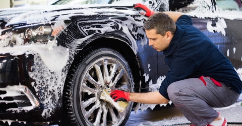 Man worker washing car's alloy wheels on a car wash