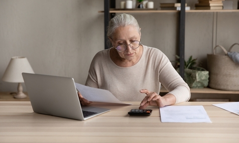 a woman using a calculator while holding a paycheck page
