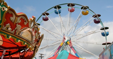 Fair carnival rides and tent top against blue sky