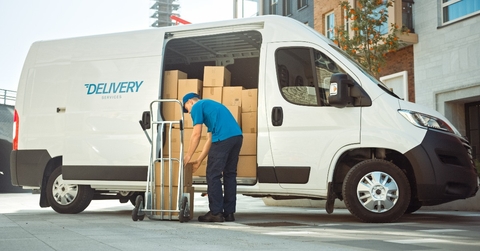 courier takes out cardboard box package from opened delivery van 