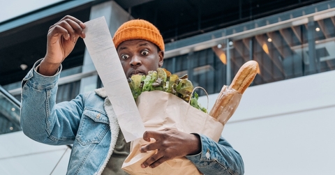 man in denim jacket looks at sales paper receipt