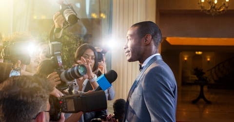 Celebrity being interviewed photographed by paparazzi at red carpet event