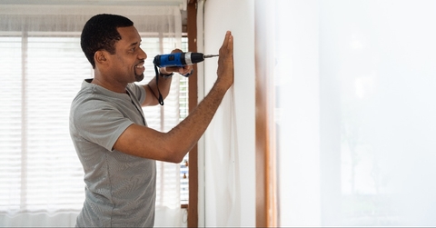 male using electric drill on the wall 