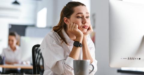 bored young woman dressed in shirt sitting at her workplace
