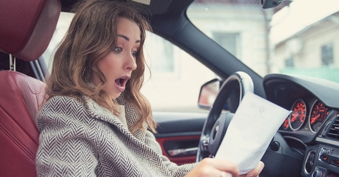 shocked woman in car reading insurance paper