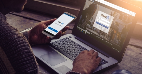 man using linkedin on smartphone and laptop