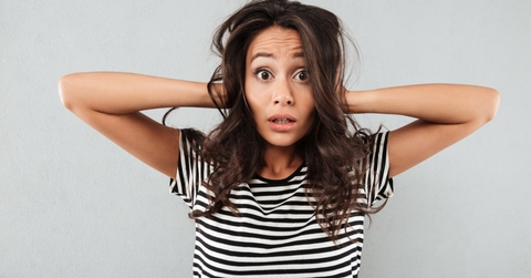 young woman holding her head stressfully in black and white striped shirt