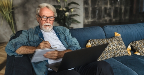 elderly man writing notes in notebook