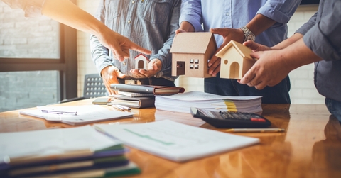 Several people in a meeting room holding model houses