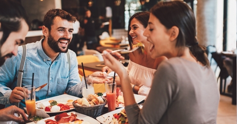 group of happy friends eating food at a restaurant