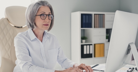 stylish senior lady with bob cut sitting on chair working at office on desktop
